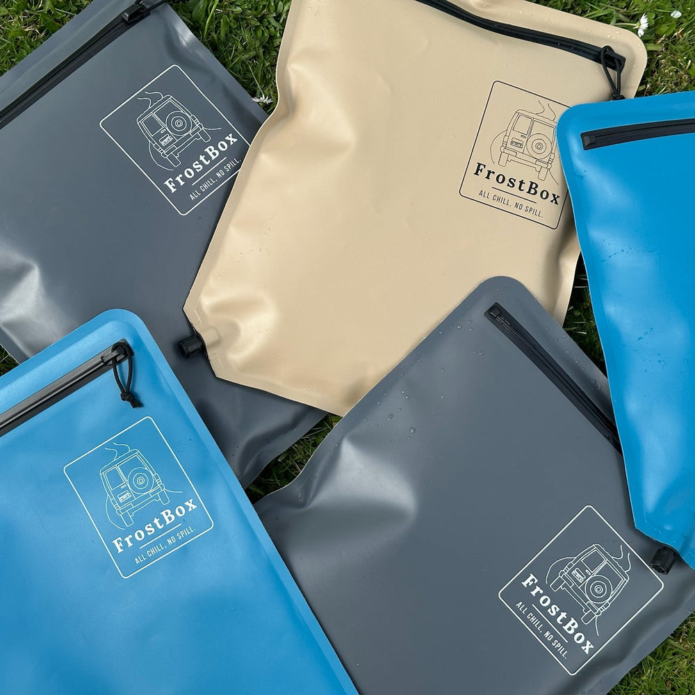 FrostBox ice bags in Sand, Charcoal and Tasman Blue laid out on the grass