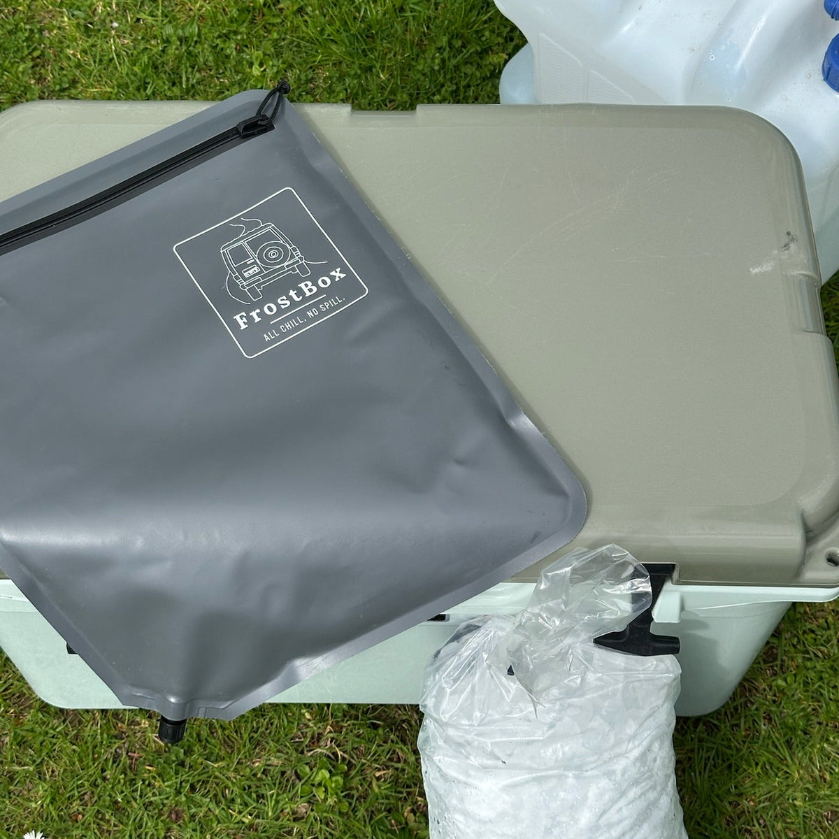 Charcoal FrostBox ice bag on a chilly bin lid next to a bag of ice